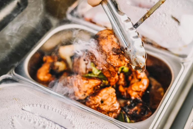 Lunch catering setup with chicken in an aluminum tray being served using tongs