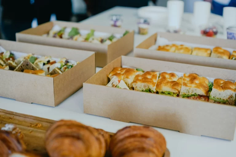 Breakfast catering setup with a serving table featuring fresh breakfast rolls, pastries, and morning dishes