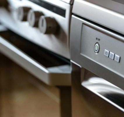 Close-up view of modern stainless steel kitchen appliances with focus on dishwasher and oven.
